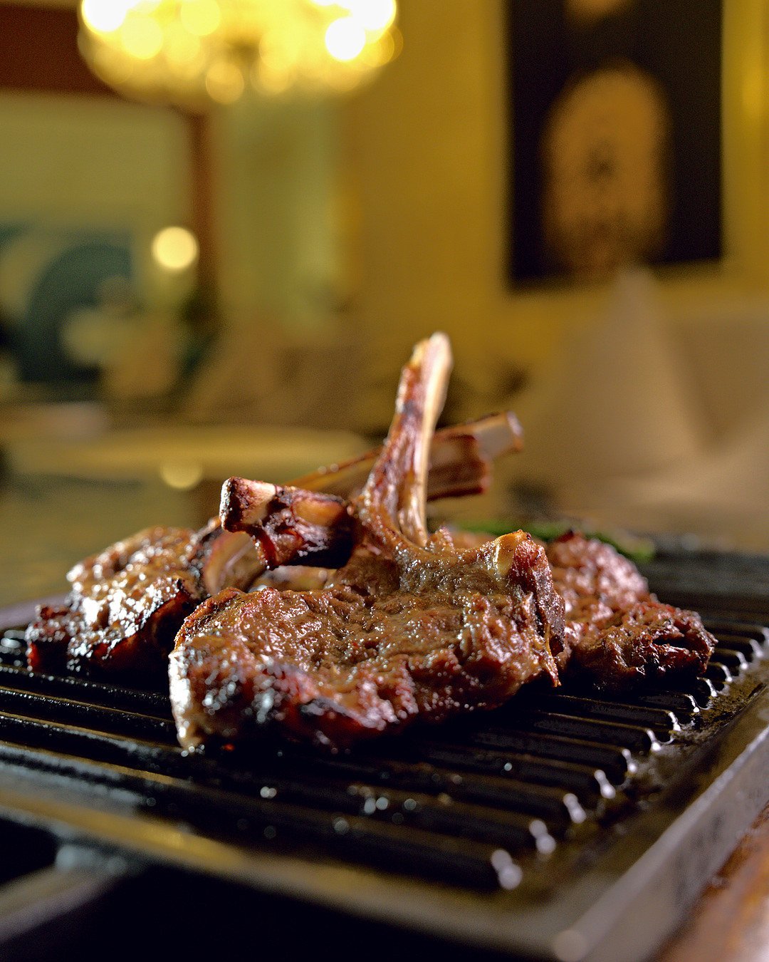 Lamb Chops on an iron grill plate, the warm room behind